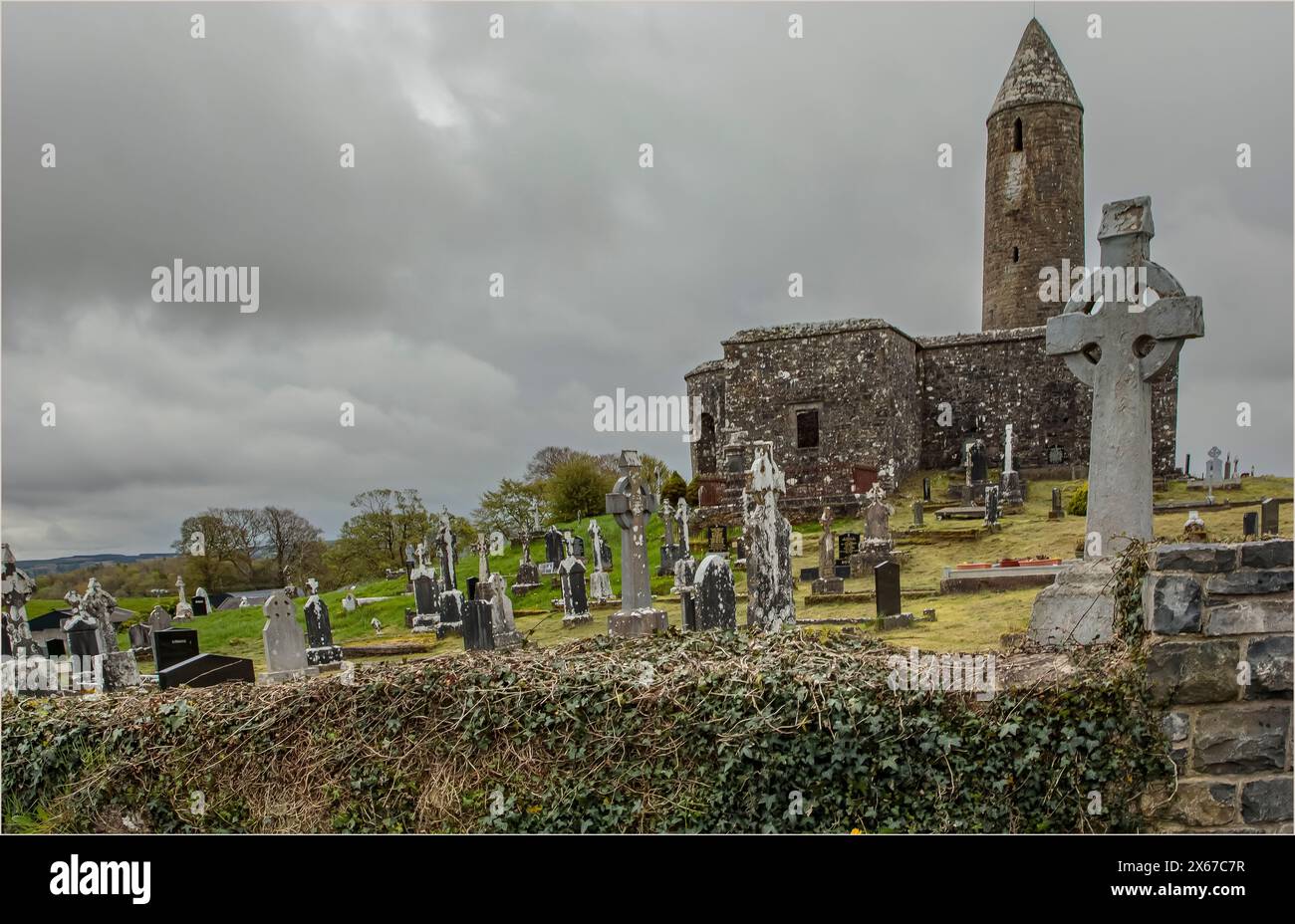 Alte runde Turmkirche mit einem stillgelegten Friedhof vor einem stimmungsvollen und stürmischen Himmel Stockfoto