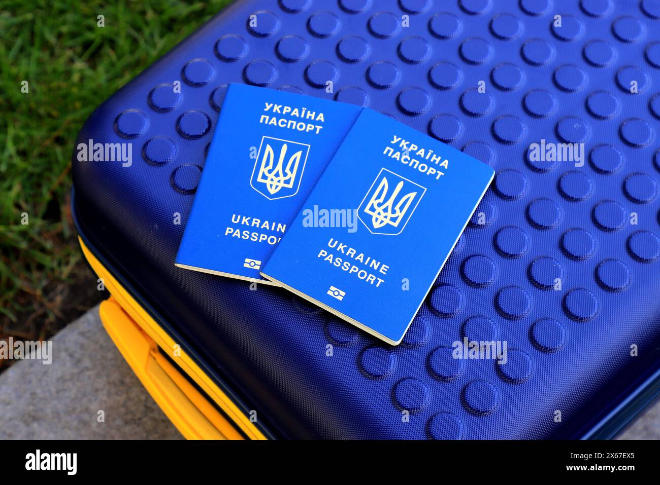 2 Pässe ukrainische Staatsbürger mit Inschrift auf Ukrainisch - Reisepass der Ukraine liegen auf gelb blauem Koffer in der Farbe der ukrainischen Flagge. Reisen, Zuflucht Stockfoto