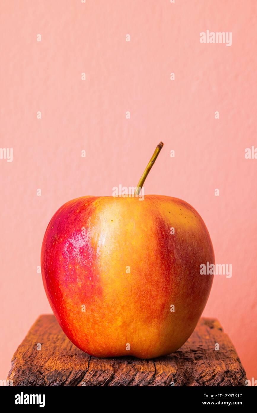 Apfel auf Holz vor pfirsichfarbenem Hintergrund Stockfoto