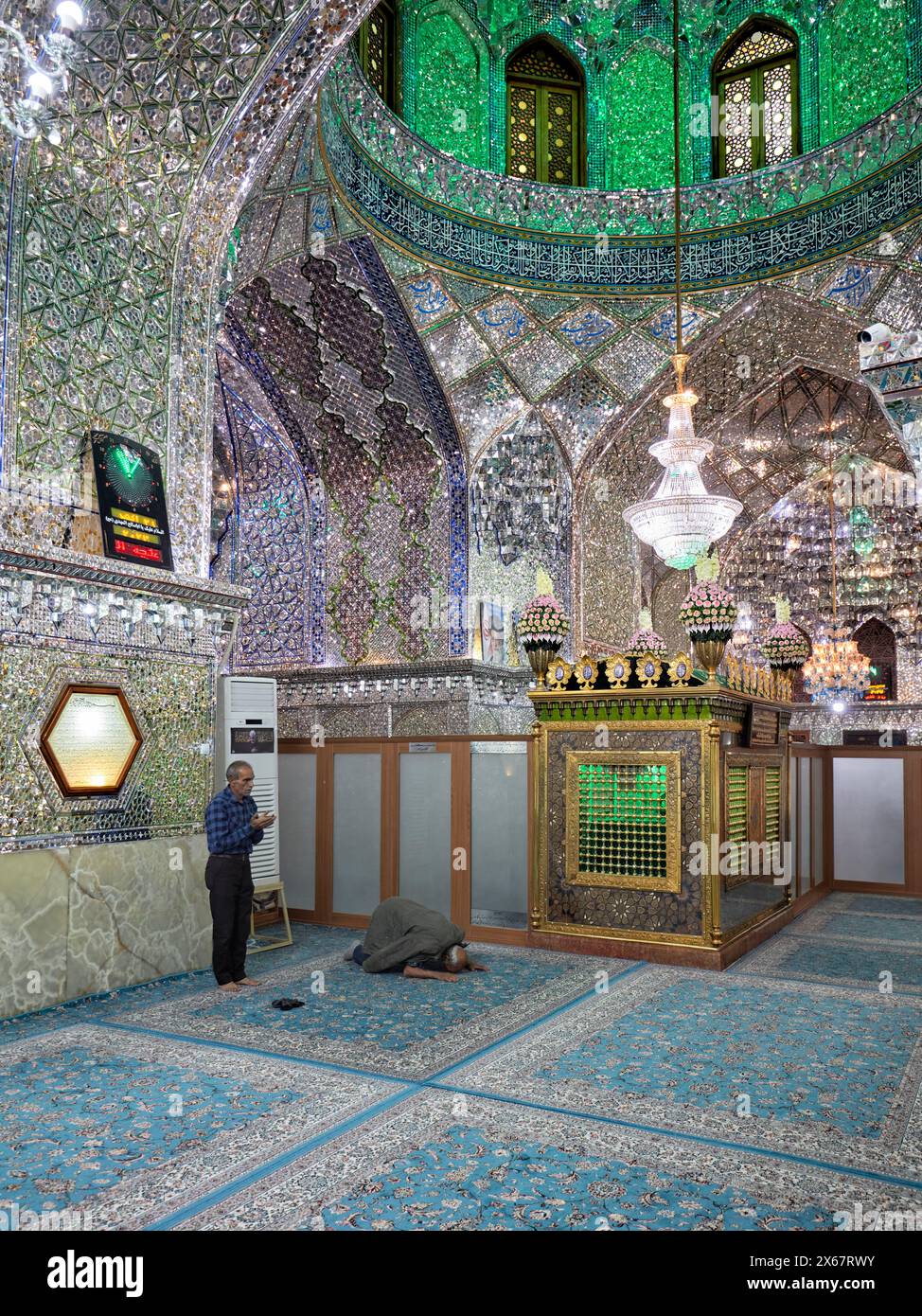 Männer beten im Ali Ibn Hamzeh Heiligtum, das im Inneren aufwendig mit glänzenden Spiegelfliesen (aina-kari) verziert ist. Shiraz, Iran. Stockfoto