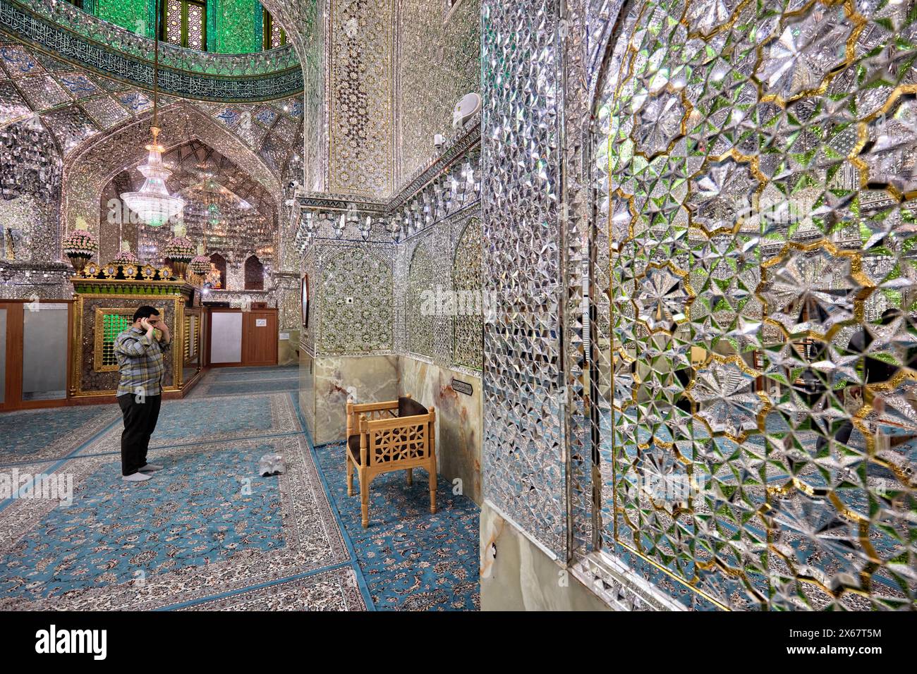 Ein Mann betet im Ali Ibn Hamzeh Heiligtum, das im Inneren aufwendig mit glänzenden Spiegelfliesen (aina-kari) verziert ist. Shiraz, Iran. Stockfoto