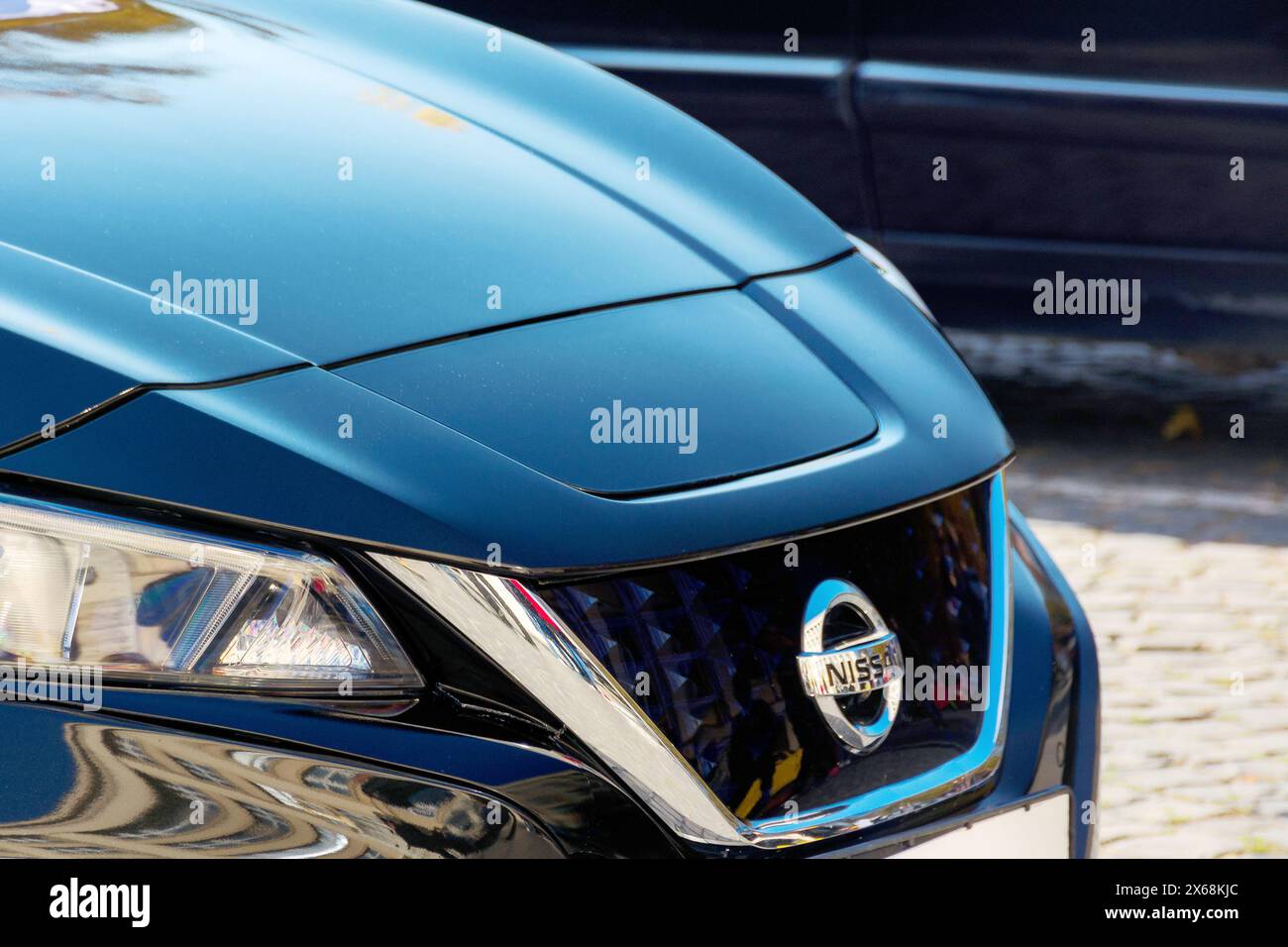uschgorod, ukraine - 31. oktober 2021: nissan-Ornament auf dem Kühlergrill eines blauen Elektroautos. Nahaufnahme im Freien Stockfoto