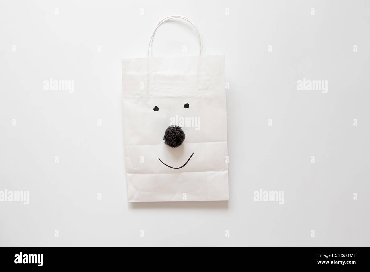 Papiertüte mit einem Lächeln und einer Nase von einem Bubo auf weißem Hintergrund, Papierverpackung Stockfoto