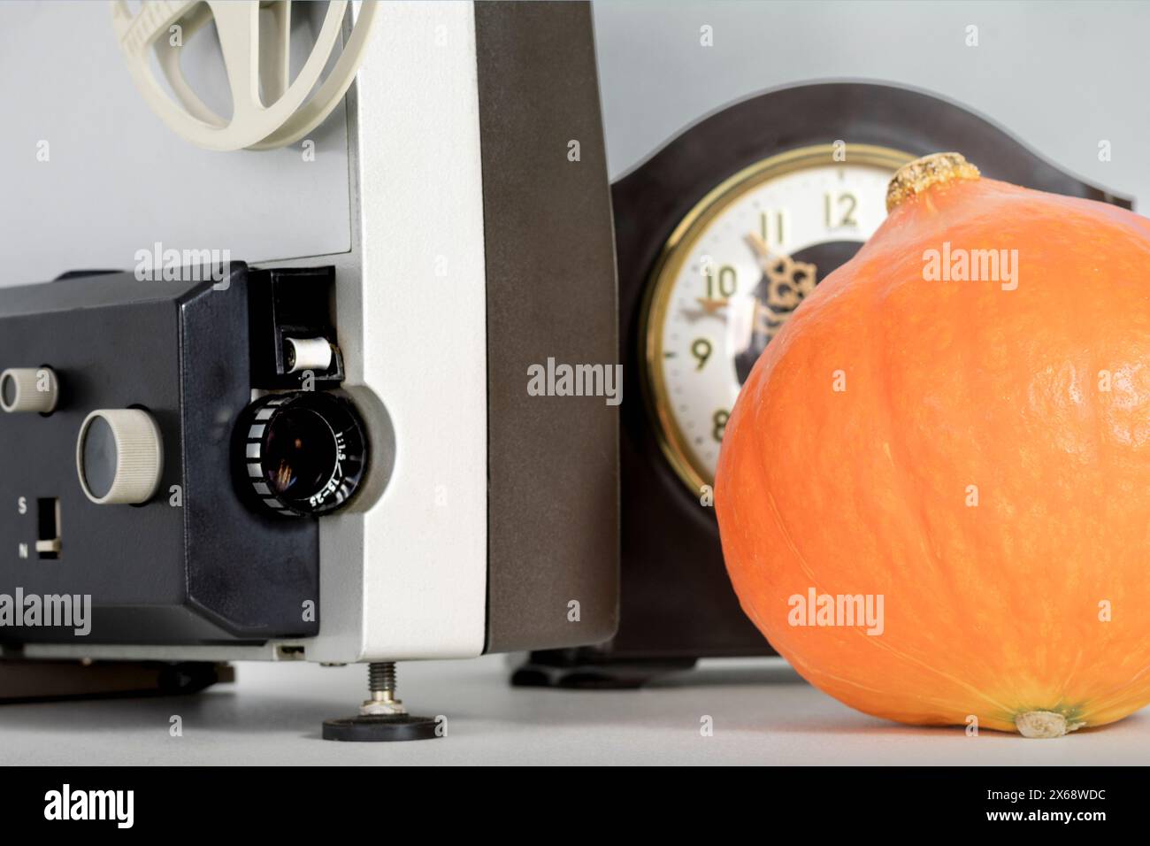 Halloween-Filmkonzept. Zeit für Horrorfilme. Filmprojektor, Kürbis und Uhr Stockfoto