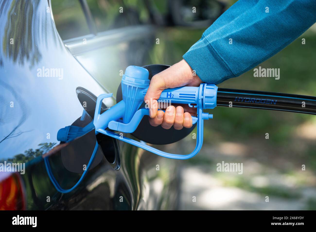Der Mann hält eine Wasserstoffdüse. Betanken des Autos mit Wasserstoffkraftstoff. Konzept... Stockfoto