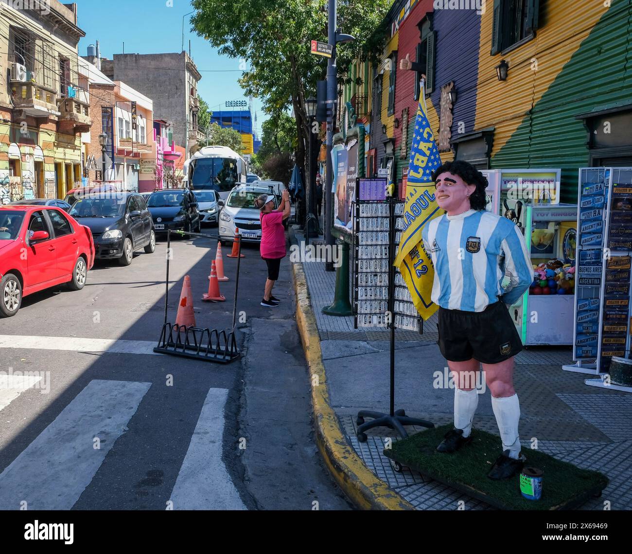 La Boca, Buenos Aires, Argentinien - die Figur der Fußballlegende Diego Maradona begrüßt Touristen vor einem Geschäft. Hinter ihm in Blau und Gelb befindet sich das Stadion La Bombonera Stockfoto