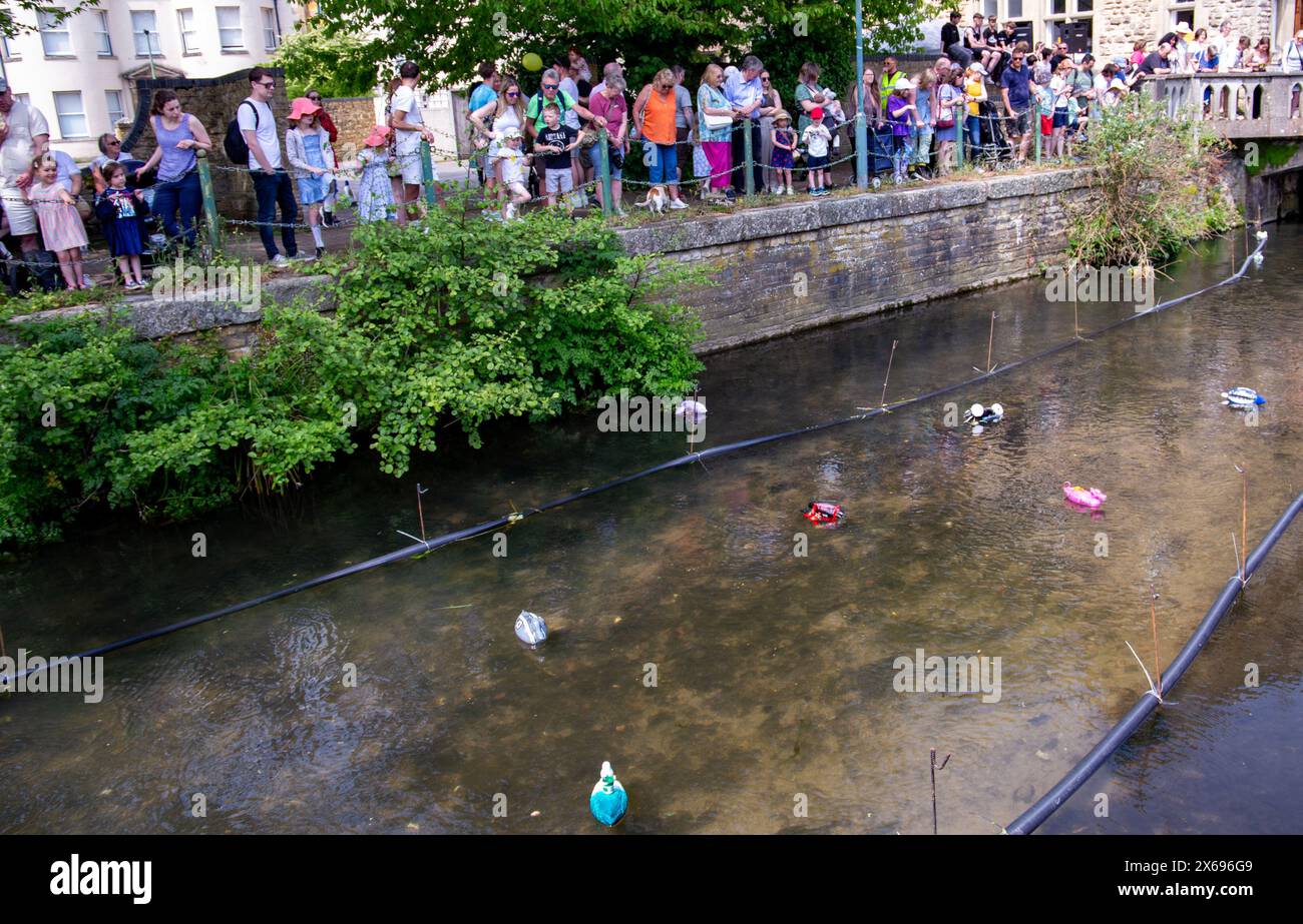 Zuschauer beobachten ein Entenrennen mit Gummienten, die während eines festlichen Gemeindeevents in einem Fluss schwimmen Stockfoto