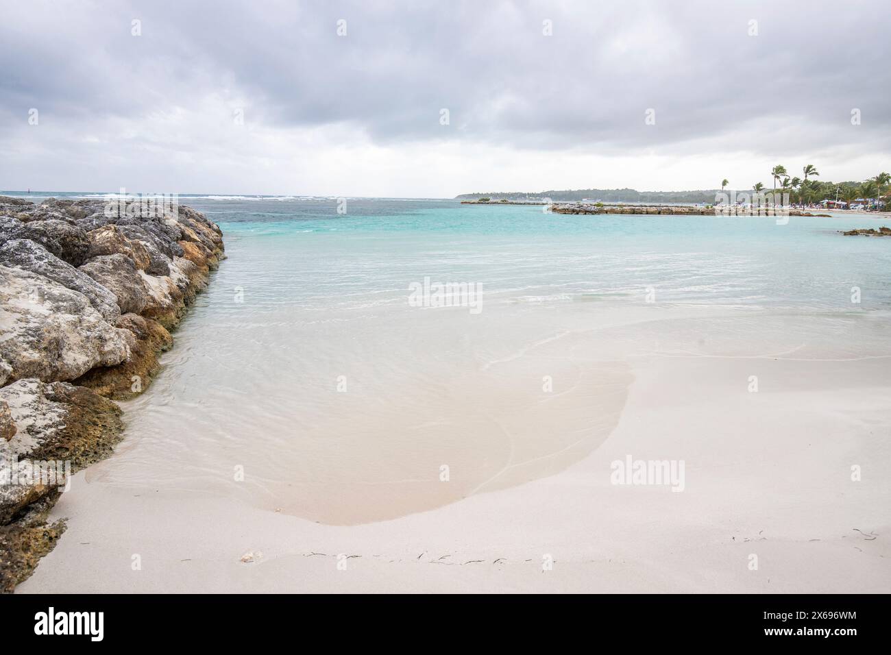 Karibischer Traumstrand mit Palmen, weißem Sandstrand und türkisfarbenem, kristallklarem Wasser im Meer. Flache Bucht an einem bewölkten Tag. Plage de Sainte Anne, Grande Terre, Guadeloupe, Französische Antillen Stockfoto