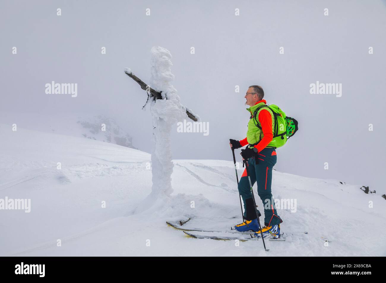 italien, Trentino, Primiero San Martino di Castrozza, Skibergsteiger in der Nähe eines vollständig mit gefrorenem Schnee bedeckten Kreuzes in der Nähe des Gipfels Juribrutto, Dolomiten Stockfoto