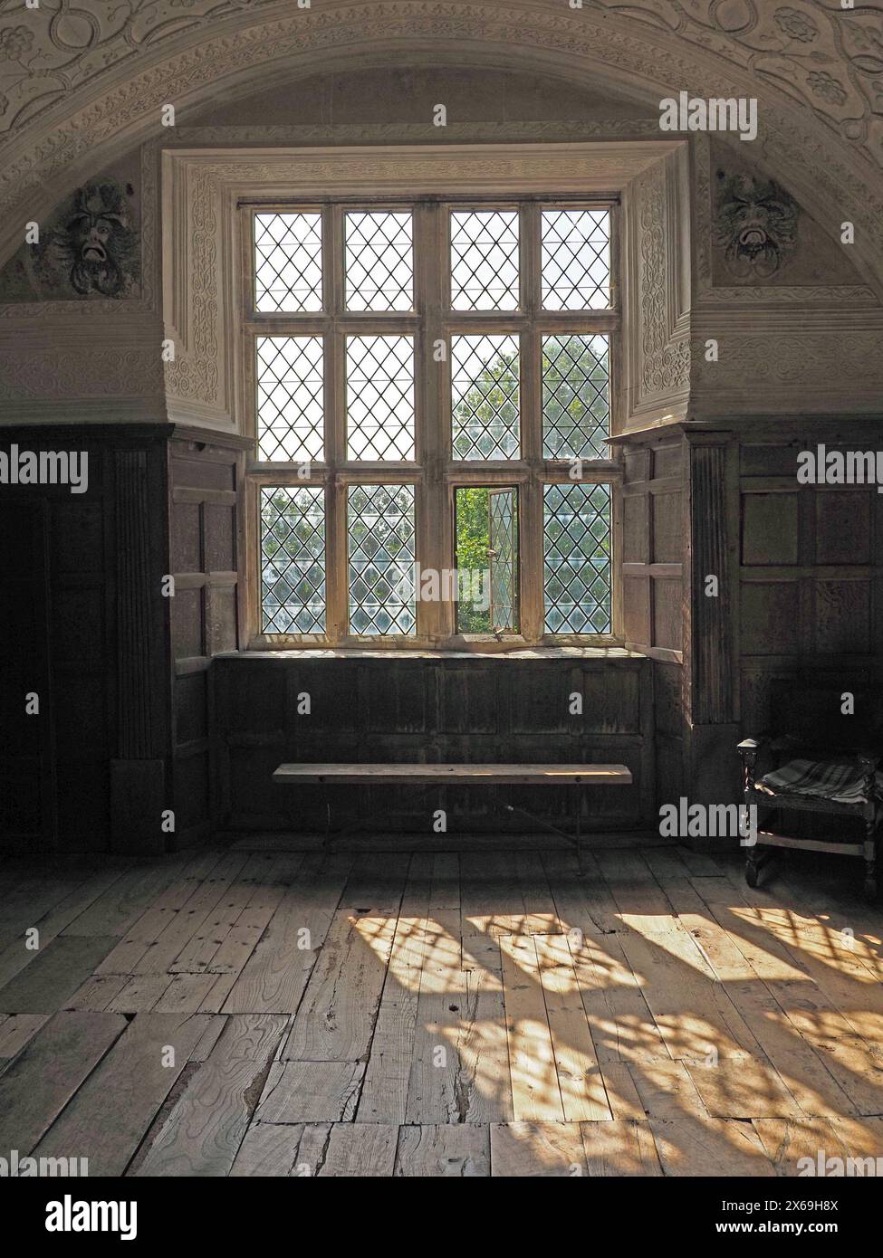 Sonnenlicht strömt durch ein altes Pfostenfenster in einem historischen Haus und wirft Schatten auf Holzdielen Stockfoto