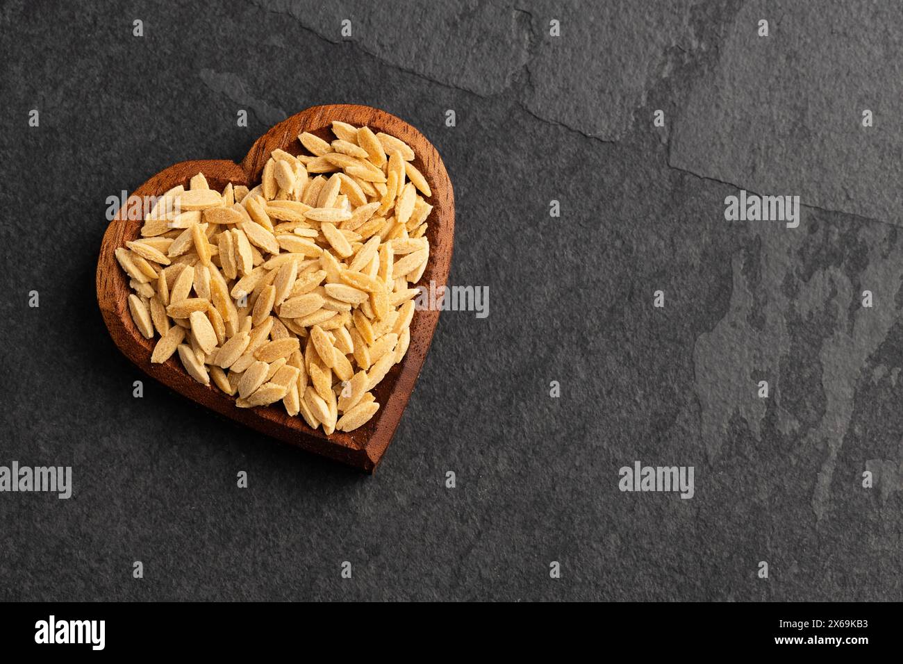 Risoni, Bio-Pasta in herzförmiger Schüssel - roh getrockneter Orzo Stockfoto