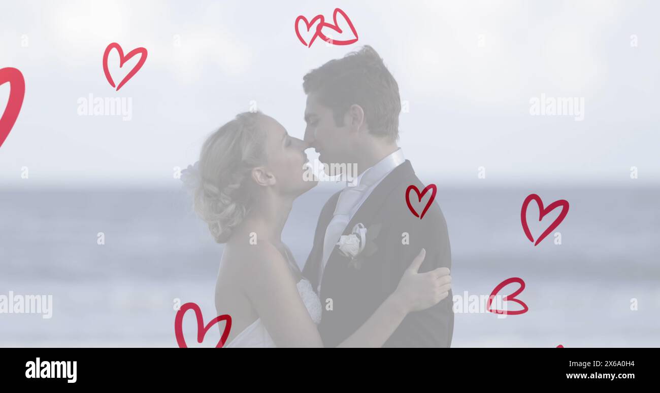 Kaukasisches Paar in Hochzeitskleidung, küsst sich am Strand Stockfoto
