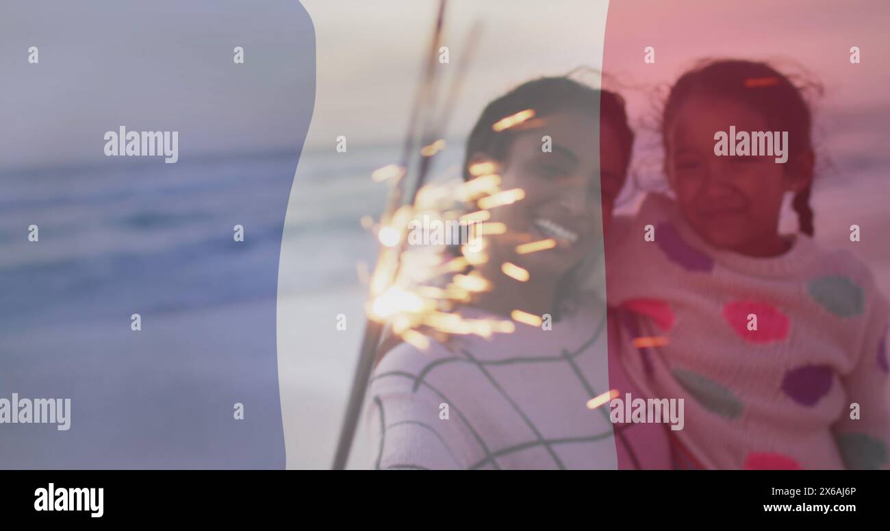 Bild der Flagge frankreichs über birassischer Mutter und Tochter, die am Strand sitzen Stockfoto