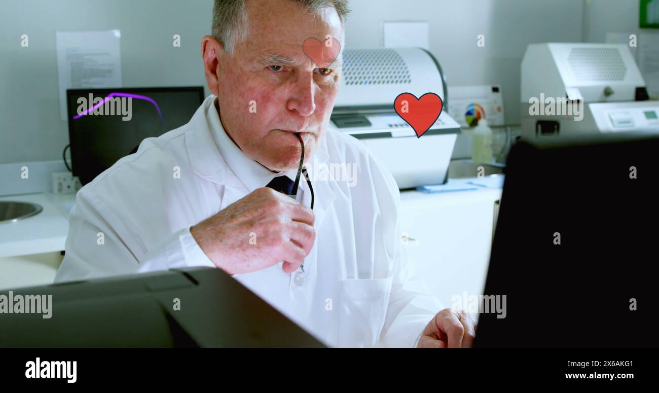 Kaukasischer Großvater/Vater, Brille trägt und auf Laptop blickt Stockfoto