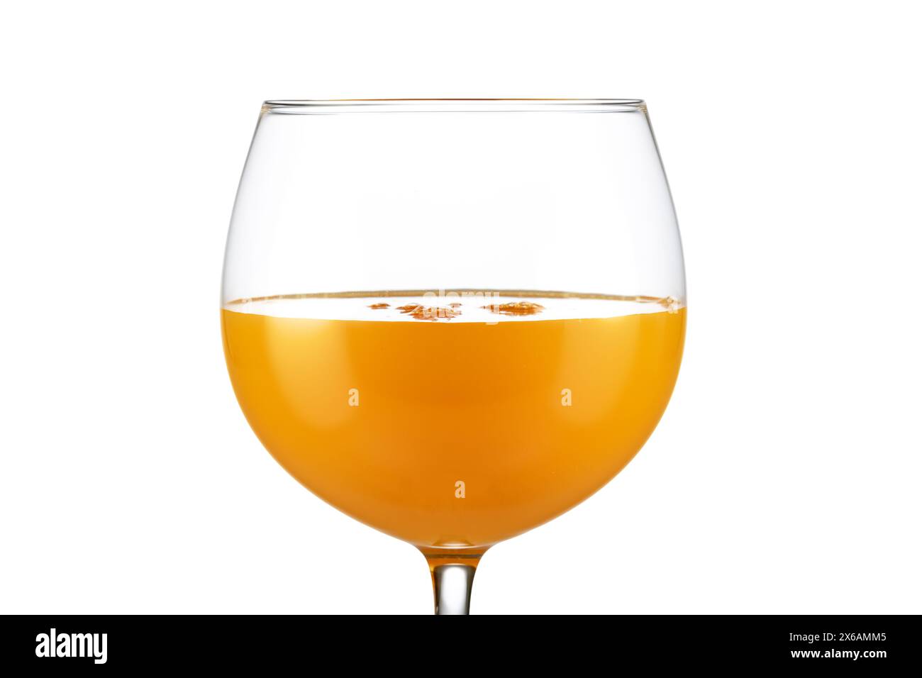 Extreme Nahaufnahme von Orangensaft in einem Ballonglas isoliert auf weißem Hintergrund. Stockfoto