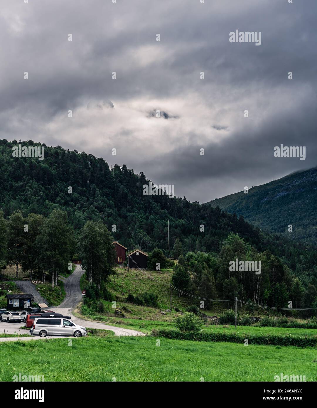 Autos parken auf dem Innerdalen-Nationalpark-Parkplatz mit den Trollheimen-Gebirgszügen, die nachmittags von weißen Wolken bedeckt sind. Møre og Romsdal in Norwegen Stockfoto