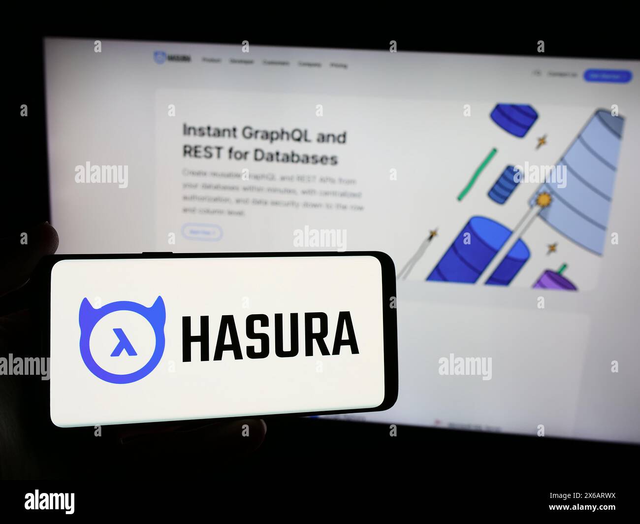 Person mit Smartphone und Logo des US-amerikanischen Softwareentwicklungsunternehmens Hasura Inc. Vor der Website. Schwerpunkt auf dem Display des Telefons. Stockfoto