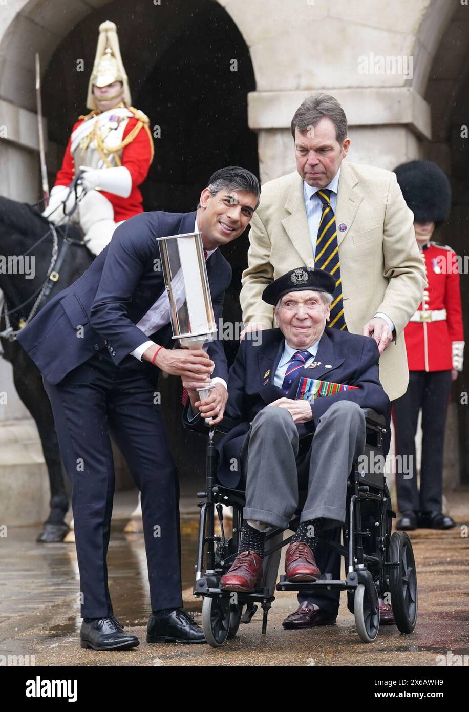 Premierminister Rishi Sunak überreicht die Fackel of Commonwealth war Graves Commission (CWGC) an den 99-jährigen D-Day-Veteranen Peter Kent, der den 80. Jahrestag der D-Day-Landung auf dem Tilt Yard, Horse Guards, Whitehall feierte. Um das Relais zu starten, wird die Fackel von einem Veteranen an einen dienenden Offizier, einen Kadett und einen CWGC-Freiwilligen übergeben - symbolisiert die Botschaft des D-Day, der durch die Generationen weitergegeben wird. Bilddatum: Dienstag, 14. Mai 2024. Stockfoto