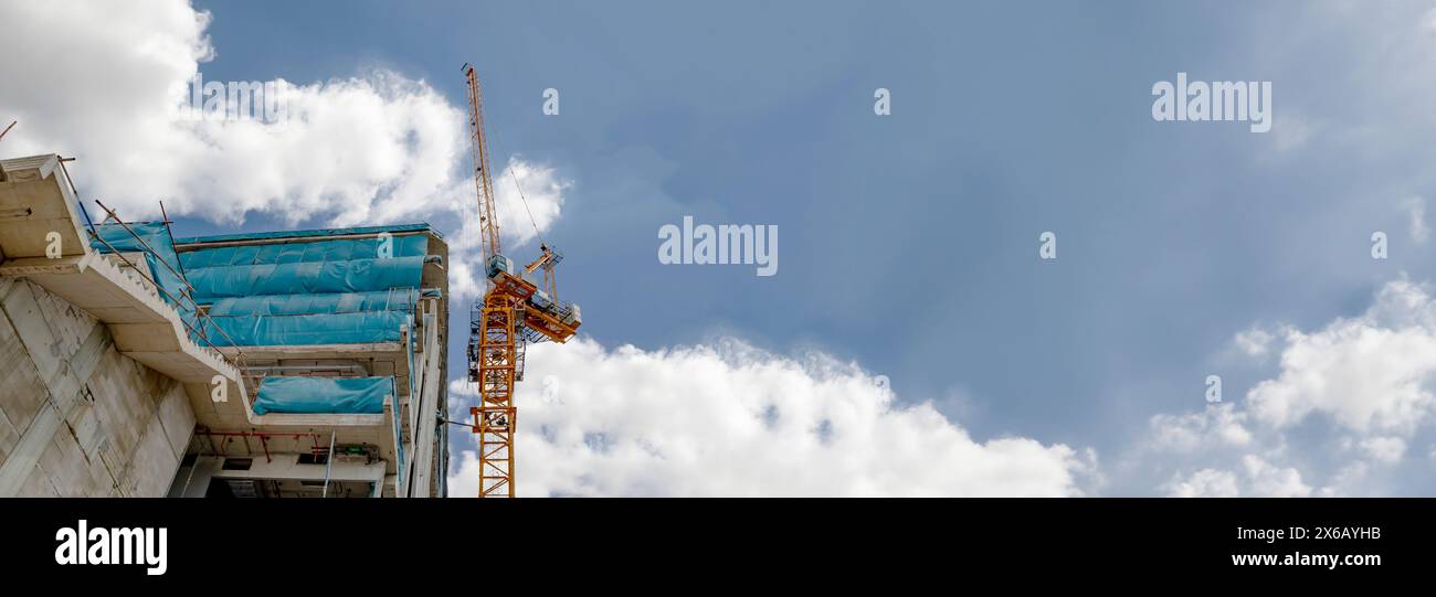 Über den Turmkran bei der Baustelle und den blauen Himmel Stockfoto