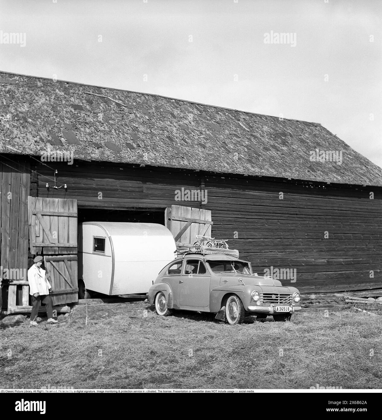Caravan in den 1950ern Eine Familie hat ihren Wohnwagen im Winter in der Scheune geparkt und es ist an der Zeit, den Wohnwagen für den Sommerurlaub zu nutzen. Das Auto ist ein Volvo PV. Conard Ref. 3722 *** örtlicher Bildtitel *** Husvagnen kan vara föregångaren till husvagnen Ägget som lanserades 1955. DET första beispiellaret av den husvagnen byggdes 1948 byggdes på initiativ av Helmer Berglund i Örebro på hans eget företag SMV, Sörby Mekaniska Verkstad. Han och hustrun kunde inte enas om hur de Skulle fira sin Semester men han bestämde sig för att göra en husvagn. EN kompromiss mellan fruns önskan om en Stockfoto