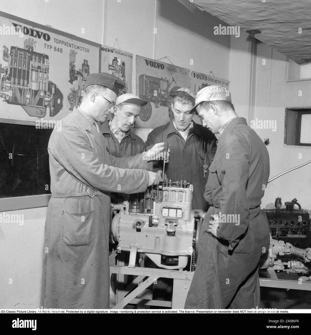 In den 1950er Jahren Schüler der Mechaniker-Schule Ernst Nilsons mit einem Teatcher an einem Volvo-Motor. Das Unternehmen war damals der größte Autohändler von Volvos und wartete die Fahrzeuge in der eigenen Garage. Die Mechaniker lernen, wie die Fahrzeuge gewartet und repariert werden. An der Wand hängen Poster verschiedener Volvo-Motoren. 3. Mai 1955. Stockfoto
