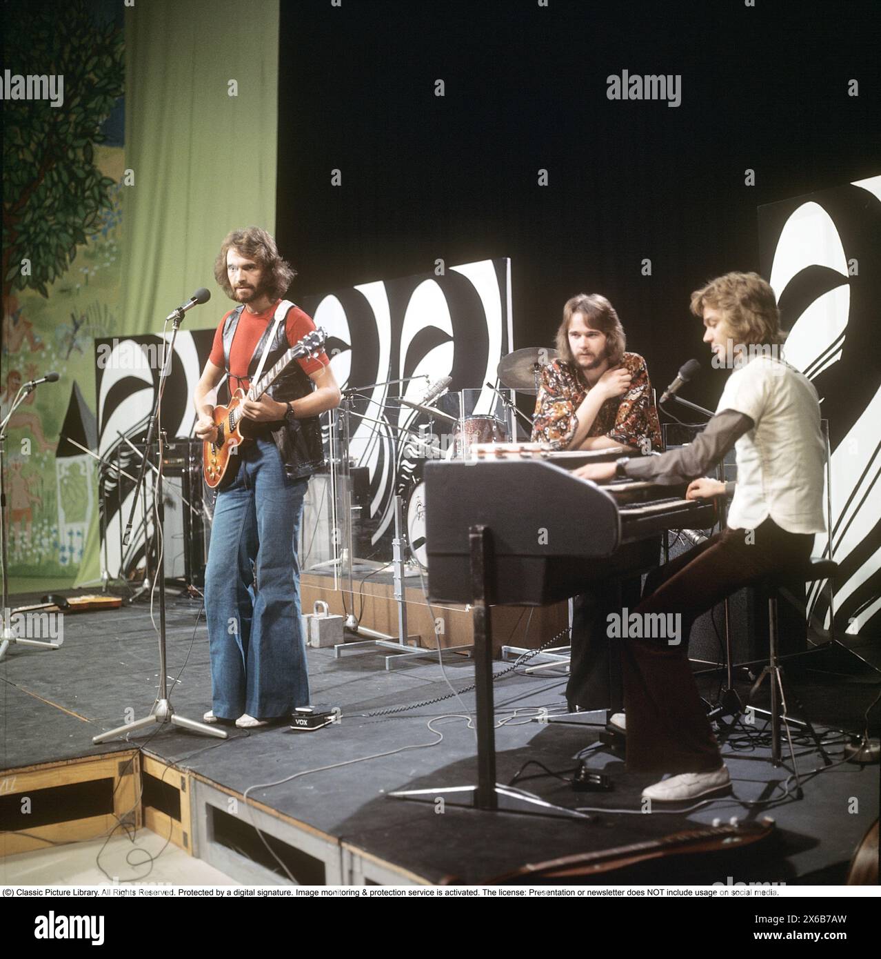 Mode der 1970er Jahre Ein junger Mann, der die typische Mode der 1970er Jahre trägt, eine Hose mit breiten Beinen. Eine Hose mit dem Namen Bell-Bottoms oder Flares, die von den Knien bis nach unten breiter wird und eine glockenartige Form des Hosenbeins bildet. Er ist Musiker Claes af Geijerstam mit seiner Band Marsfolket in einem tv-Studio und nimmt ein Programm auf. 1971. Svahn Stockfoto