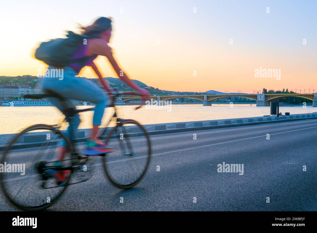 Person, die auf einer Straße am Flussufer Fahrrad fährt Stockfoto