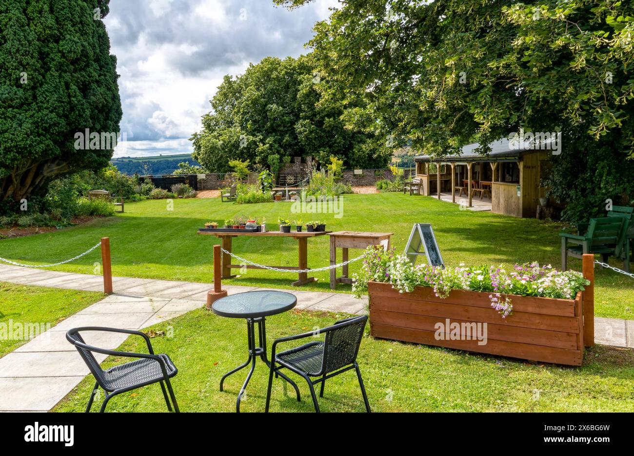 Café & ruhige Gartenszene in Great Torrington Castle Community Gardens mit Grenzmauer, Geländern, Treppen, Bäumen mit Blick auf den ländlichen Raum. Stockfoto