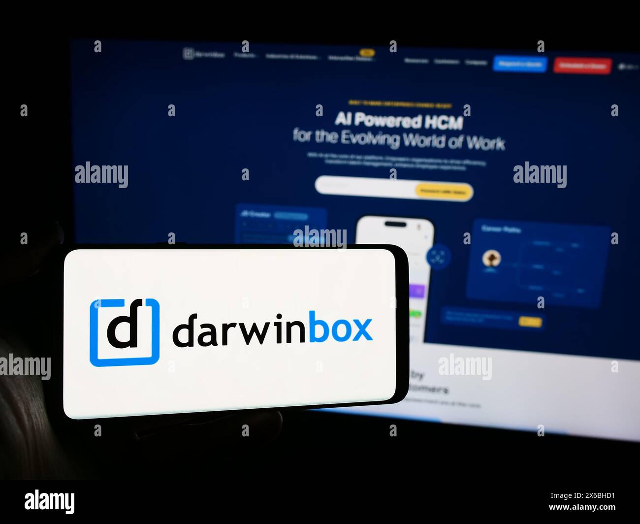 Person, die ein Mobiltelefon mit dem Logo des indischen Unternehmens Darwinbox Digital Solutions Pvt. Ltd. Vor der Webseite hält. Schwerpunkt auf dem Display des Telefons. Stockfoto