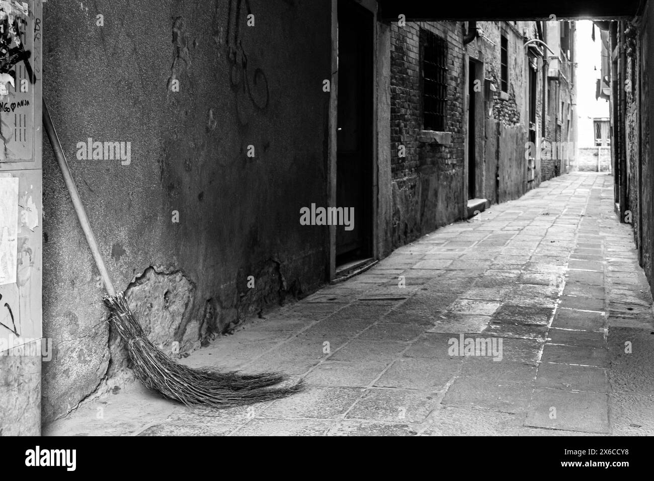 Ein einziger, altmodischer Pinsel, der sich an die Wand einer alten Gasse lehnt, in Vencie, Italien. Schwarz-weiß. Keine Personen Stockfoto