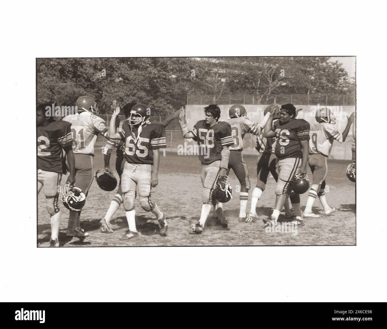 SPORTLICHES KÖNNEN. Nach einem Highschool-Fußballspiel 1982, High-Five-Spieler mit gegnerischen Spielern. Im Midwood Field in Brooklyn, New York. Stockfoto