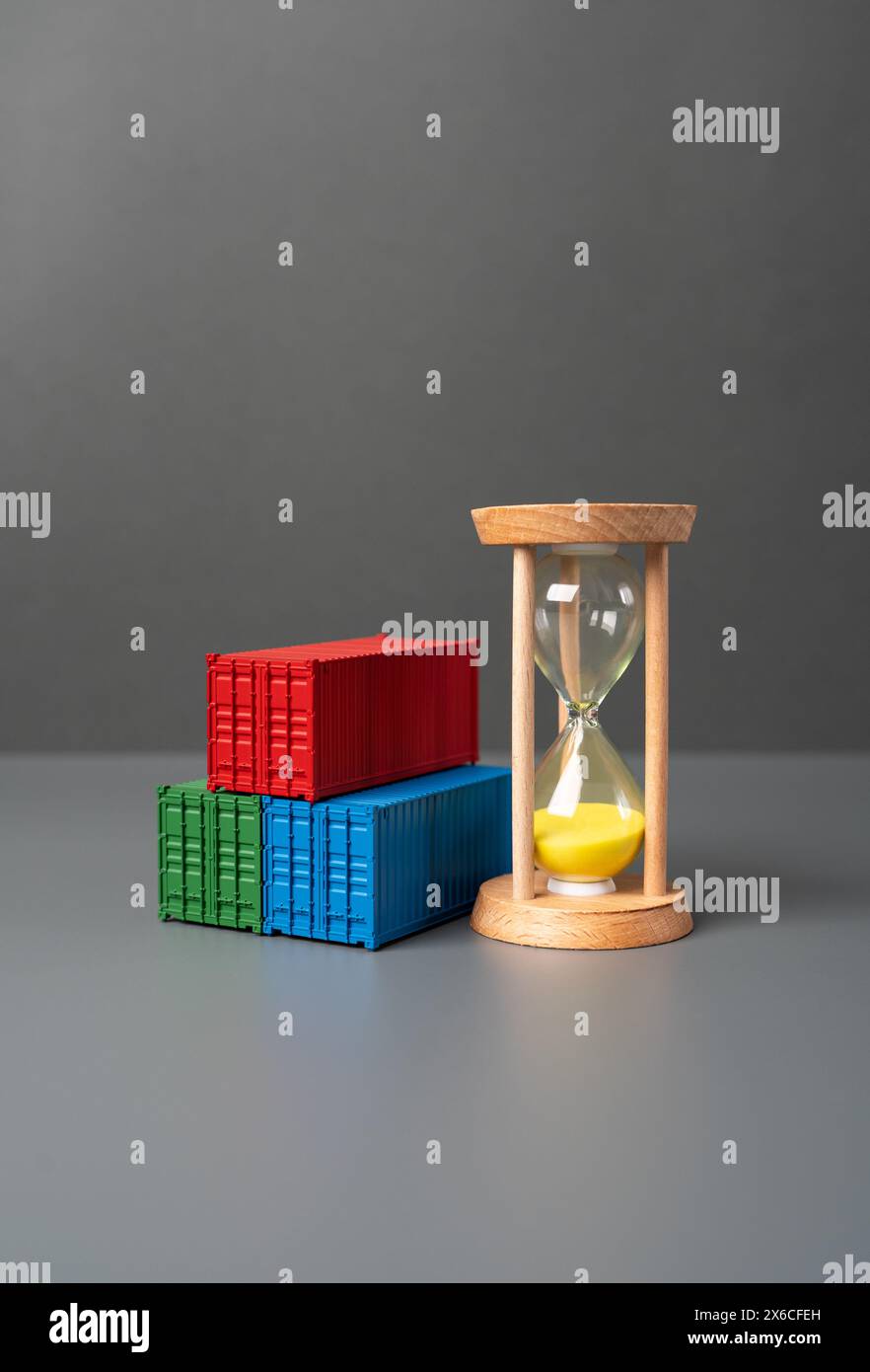 Seehandelscontainer und Sanduhr. Containerverleih. Fracht- und Versandkosten. Lieferdauer. Logistik und Transport von gewerblicher Fracht. Stockfoto
