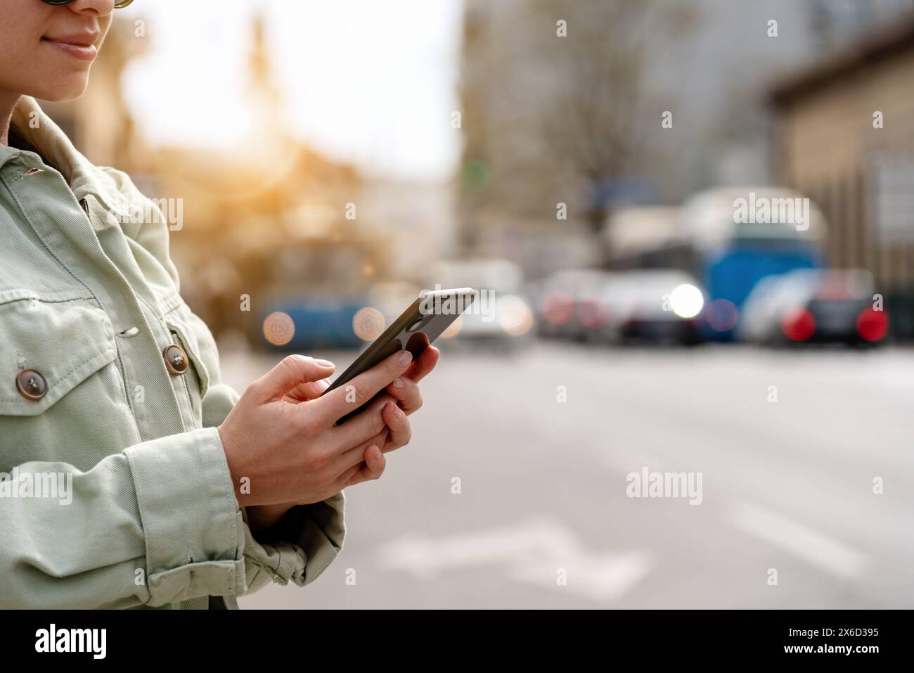 Eine Frau aus der Stadt benutzt ihr Handy, während sie neben der Stadtstraße steht. Ein Taxi mit mobiler App anfordern. Fahrpläne der öffentlichen Verkehrsmittel auf Ihrem Telefon überprüfen Stockfoto