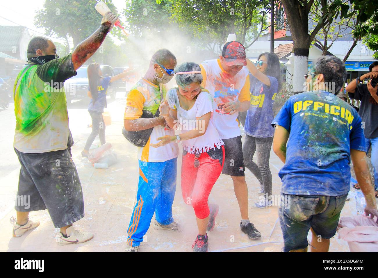 Eine Gruppe junger Leute streut mit einer anderen Gruppe bei einem Sportereignis voller Color Fun Run-Unterhaltung mit Farbpuder auf. Stockfoto