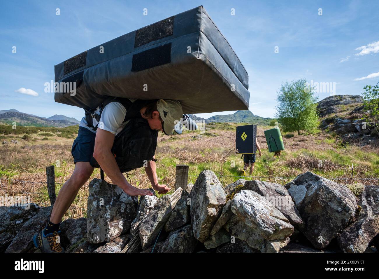 Bergsteiger, die auf einer Boulderexpedition in Nordwales mit Sicherheitsmatratzen auf dem Rücken herumklettern. Stockfoto