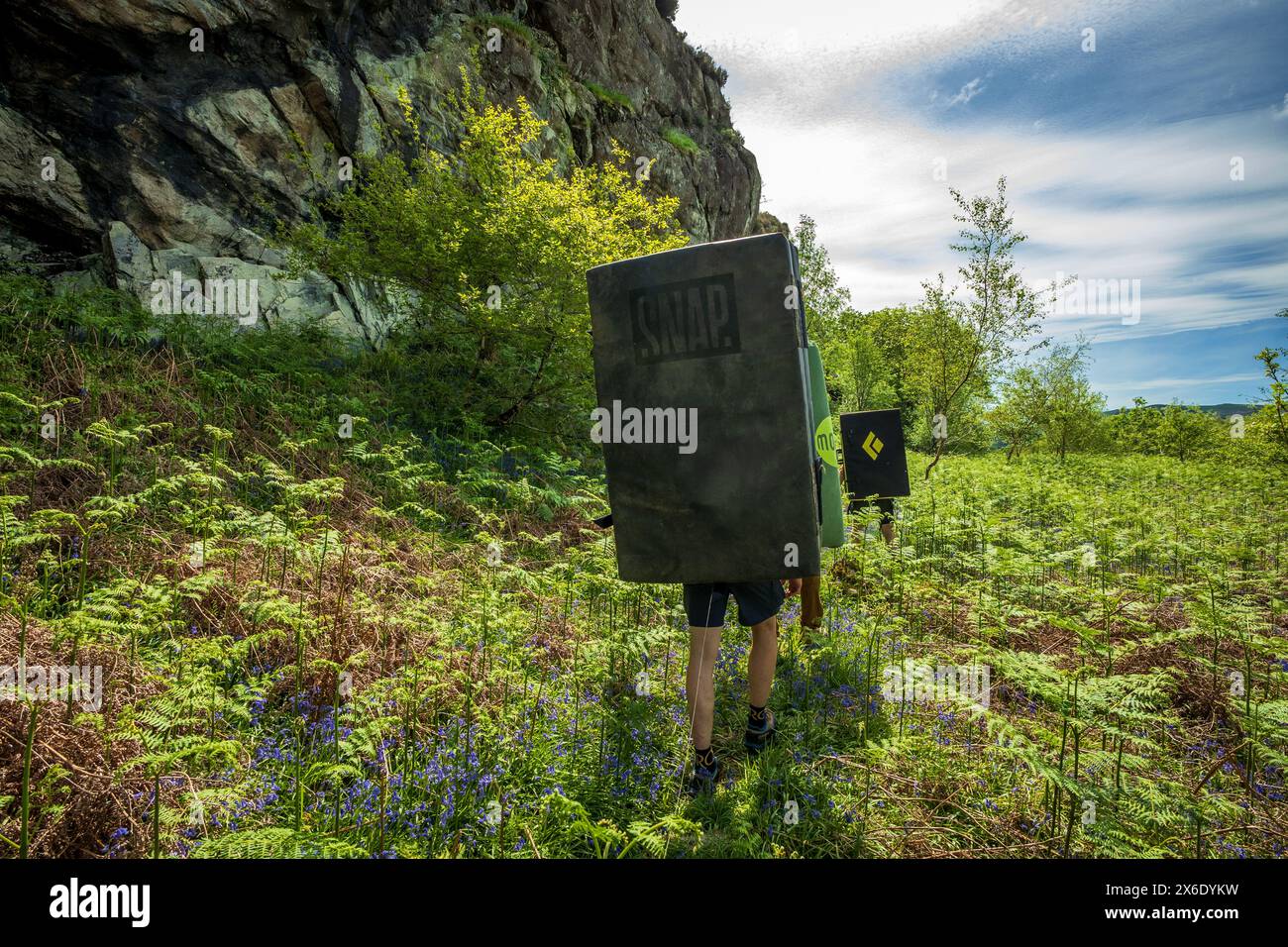 Bergsteiger, die auf einer Boulderexpedition in Nordwales mit Sicherheitsmatratzen auf dem Rücken herumklettern. Stockfoto