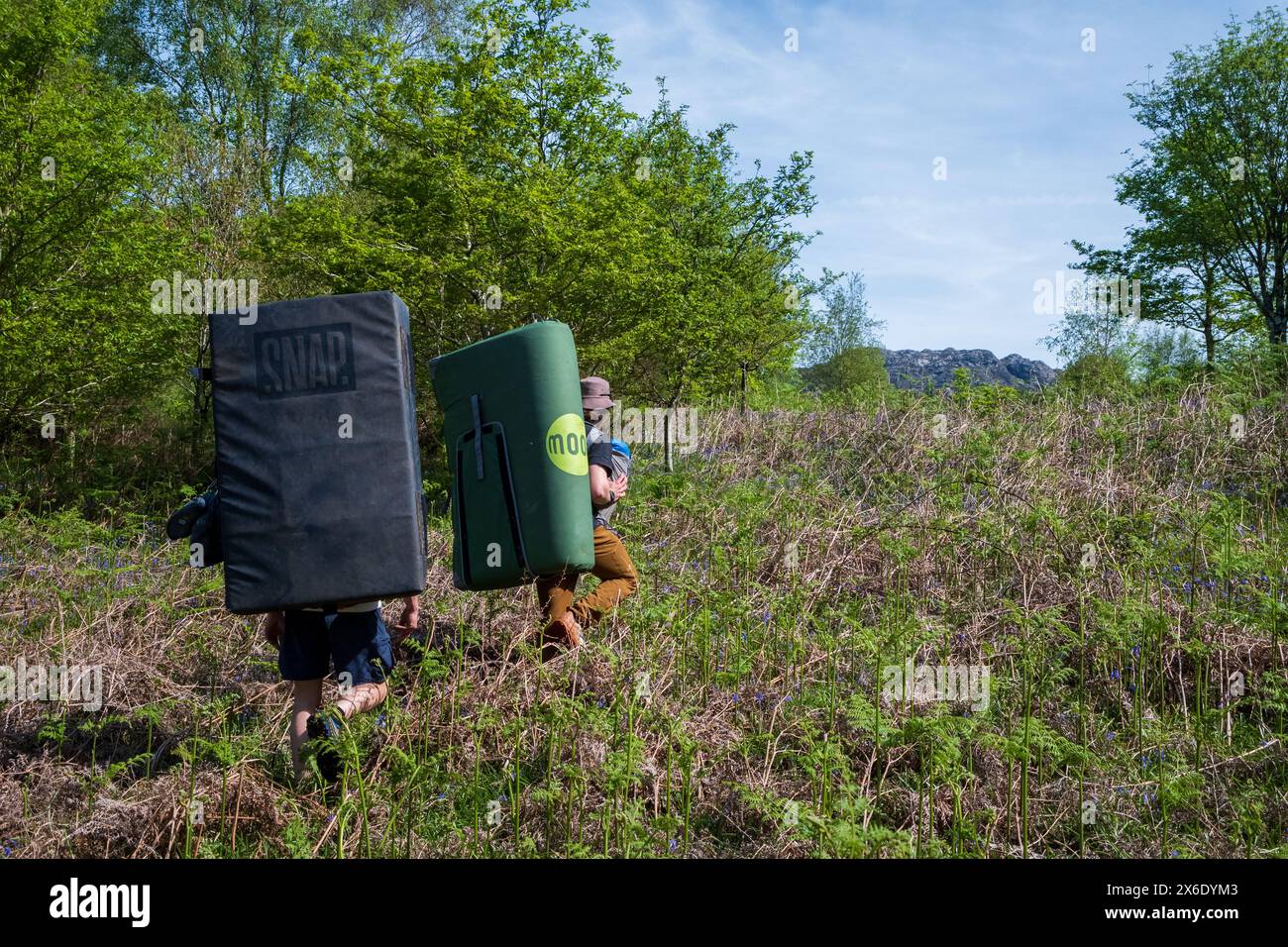 Bergsteiger, die auf einer Boulderexpedition in Nordwales mit Sicherheitsmatratzen auf dem Rücken herumklettern. Stockfoto