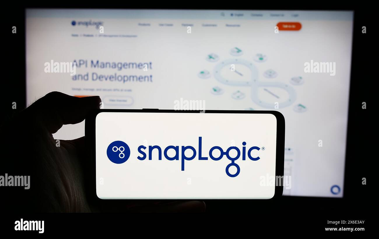 Person mit Mobiltelefon und Logo des amerikanischen Integrationssoftware-Unternehmens SnapLogic Inc. Vor der Webseite. Schwerpunkt auf dem Display des Telefons. Stockfoto