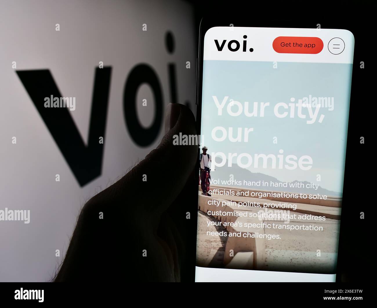 Person, die ein Handy hält, mit Webseite des schwedischen Elektrorollerunternehmens VOI Technology ab vor dem Logo. Konzentrieren Sie sich auf die Mitte des Telefondisplays. Stockfoto