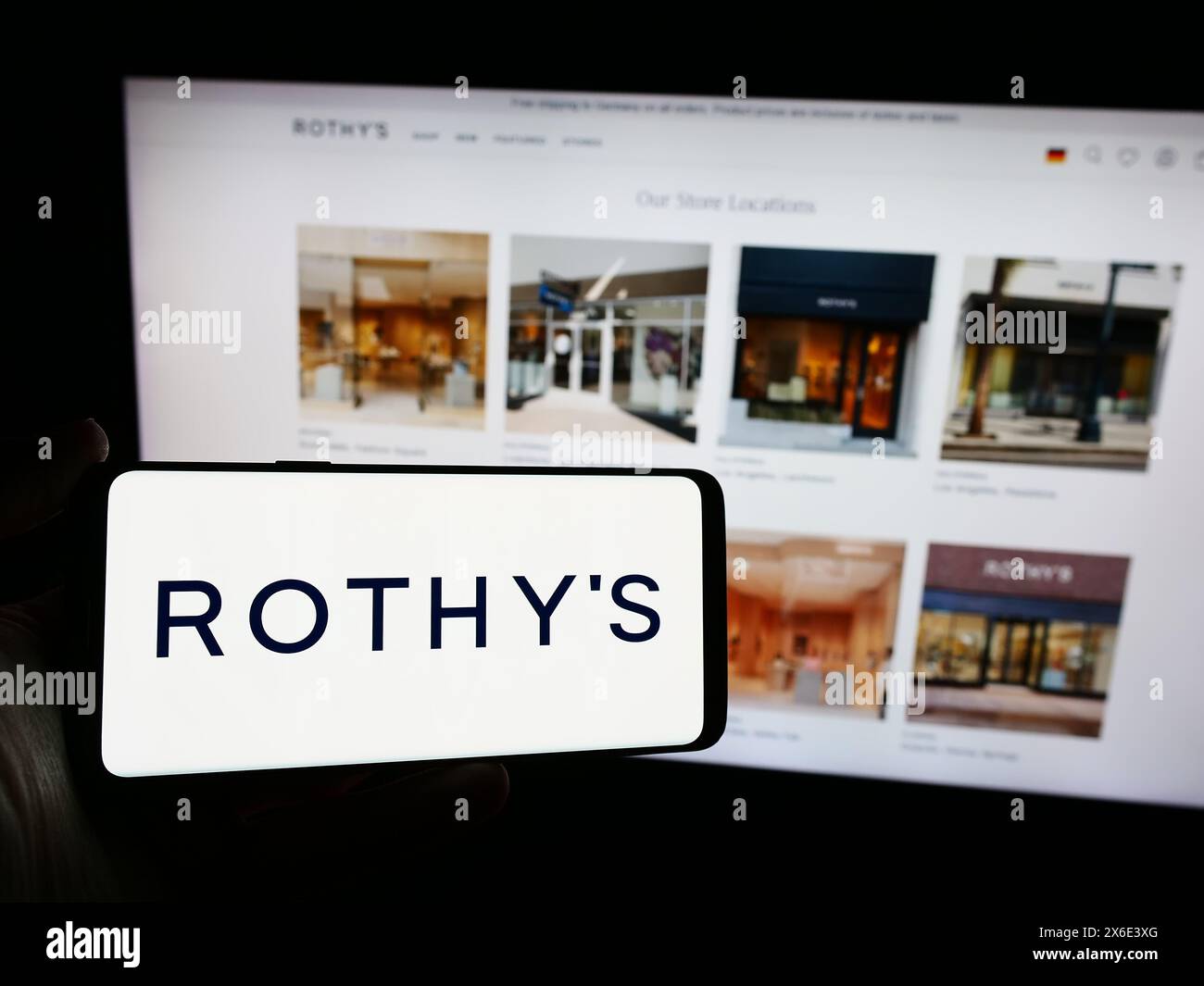Person, die ein Mobiltelefon mit dem Logo des amerikanischen Schuhhersteller Rothy's Inc. Vor der Webseite hält. Schwerpunkt auf dem Display des Telefons. Stockfoto