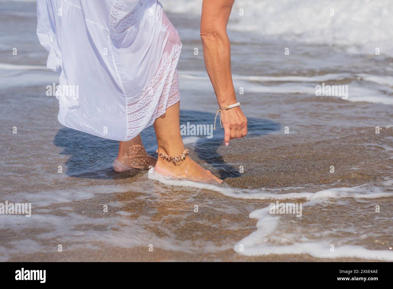 Frauenfüße, die von Meereswellen gewaschen werden Stockfoto