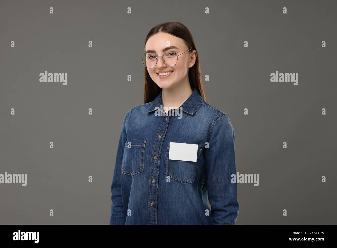 Glückliche Frau mit leerem Abzeichen auf grauem Hintergrund Stockfoto