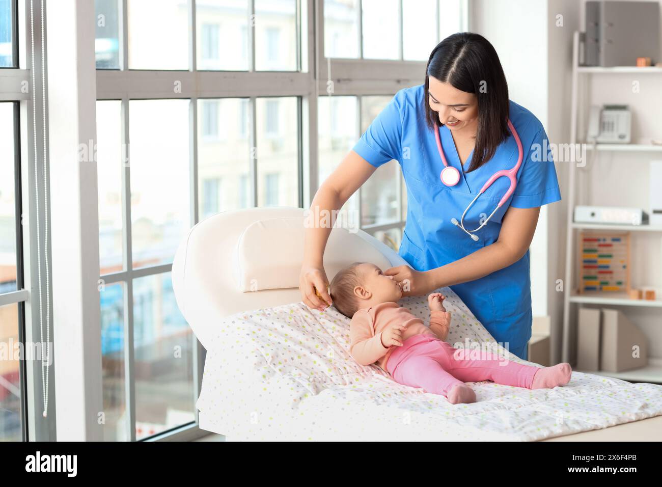 Kinderärztin, die den Kopf des kleinen Babys auf der Couch in der Klinik vermisst Stockfoto