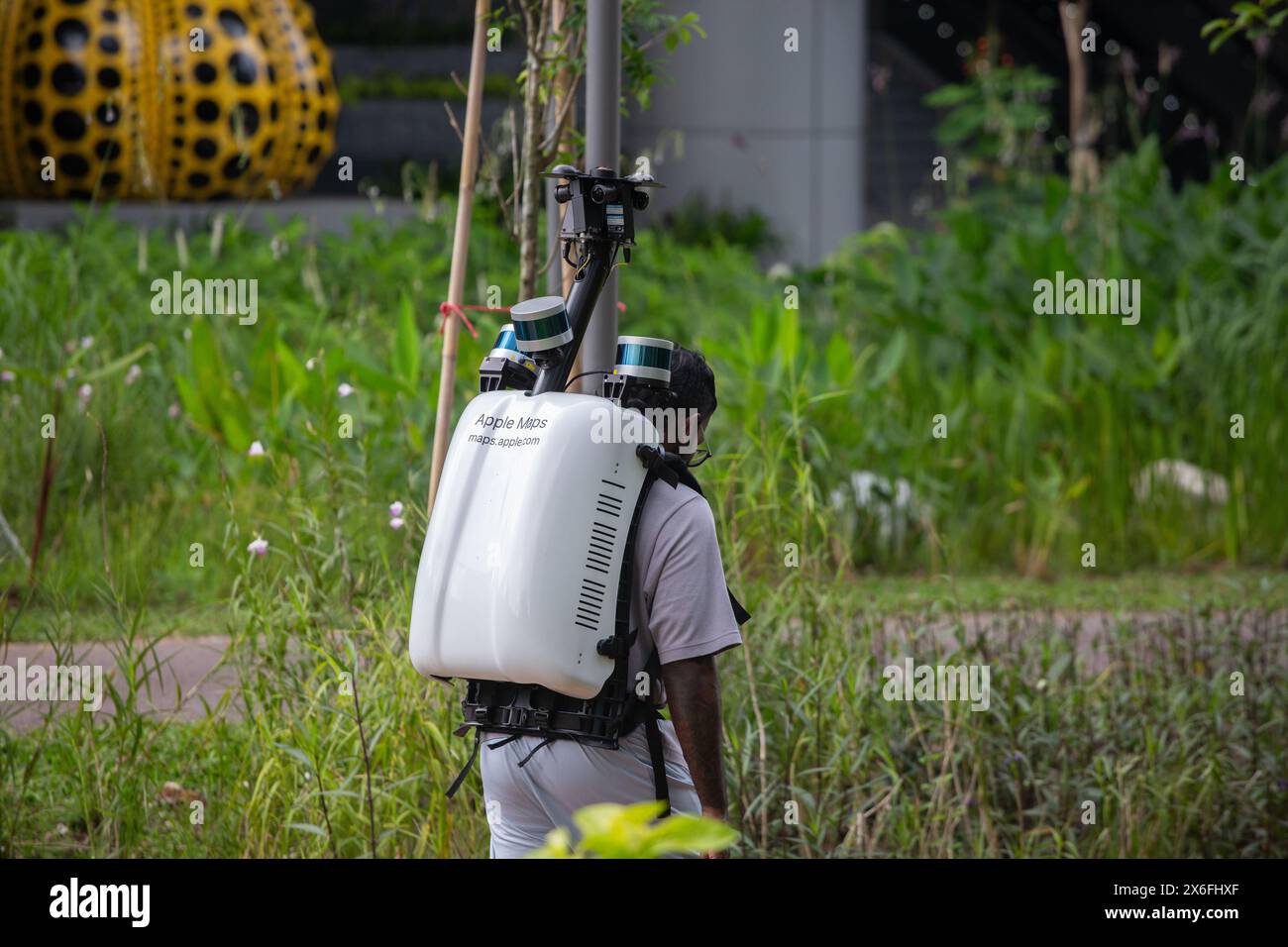 Ein Mann trägt einen schweren elektronischen Rucksack von Apple Maps, der vier Kameras darauf montiert hat, um Fotos zu machen, während er auf einer bestimmten Route unterwegs ist. Singapur. Stockfoto