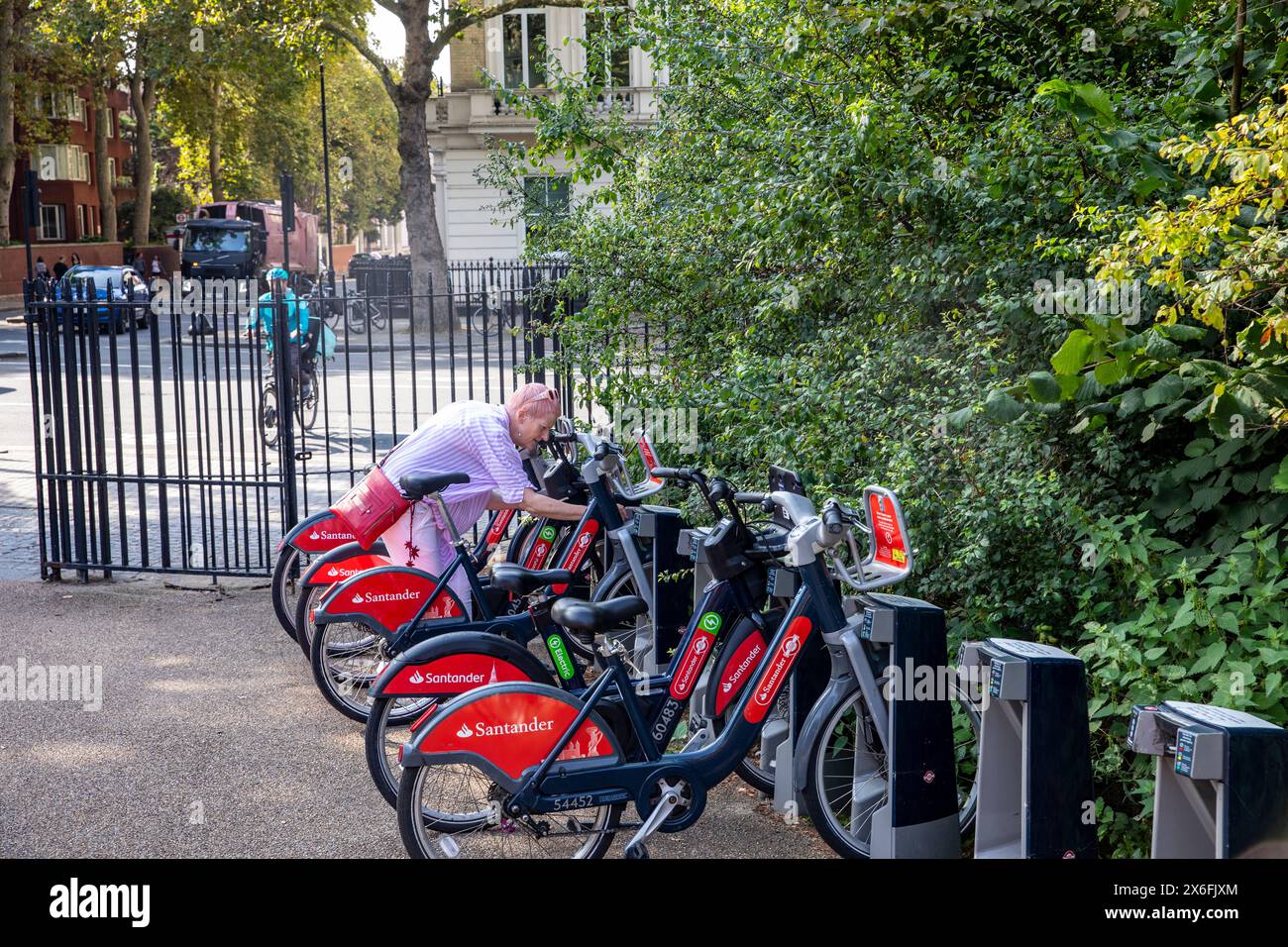 Hyde Park London Elektro-E-Bike-Verleih, Model freigelassen Frau Mitte 50 gibt den Zugangscode ein, um E-Bike aus dem Bike-Hub-Schloss im Zentrum von London zu entfernen Stockfoto