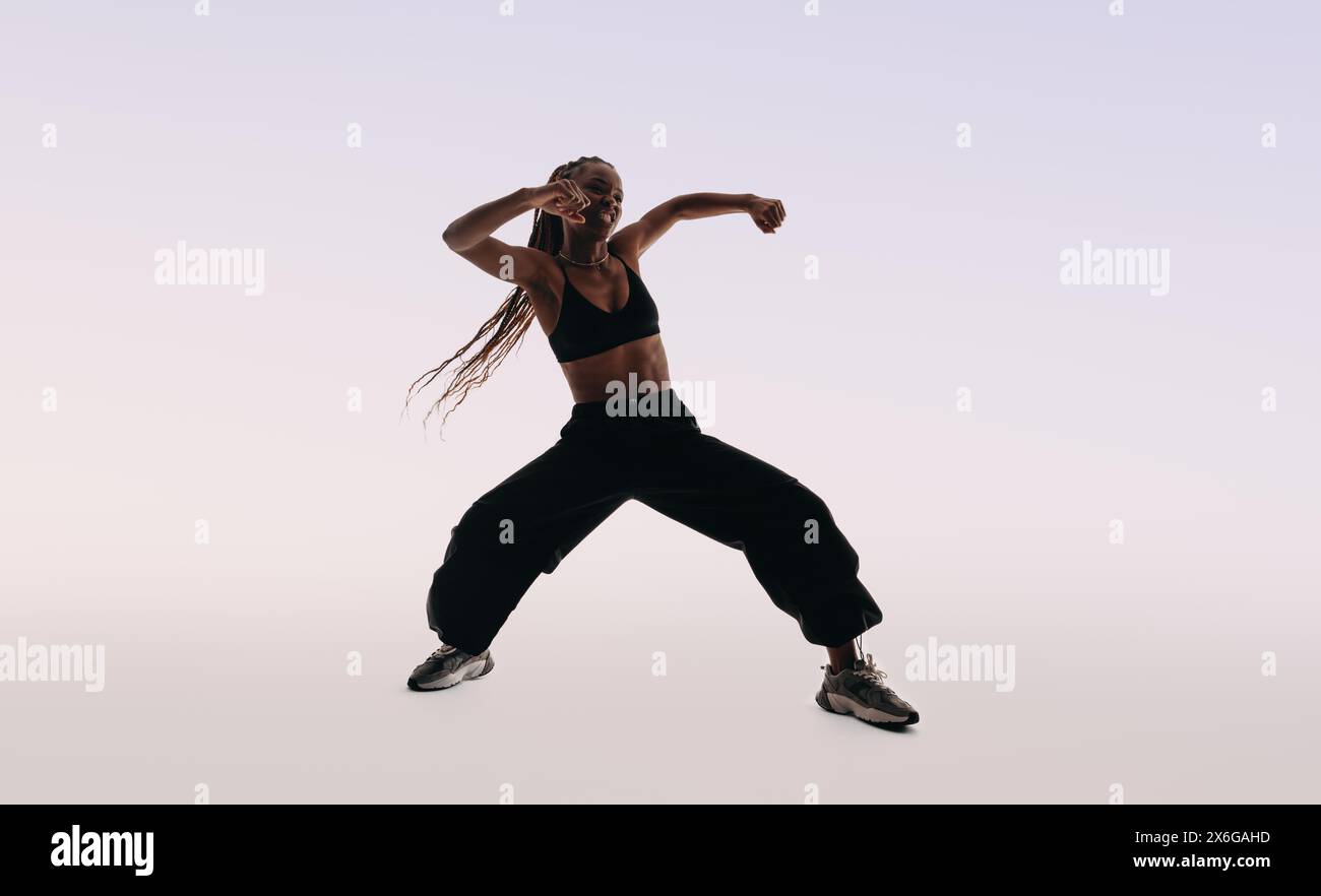 Die junge Tänzerin zeigt ausdrucksstarke Tanzbewegungen in einem Studio. Sie trägt einen Sport-BH und eine Hose. Weibliche Darstellerin, die die verkörpert Stockfoto