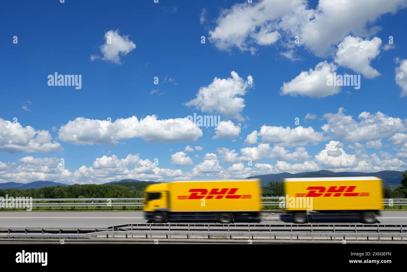 Ein gelber Lkw mit DHL-Logo fährt auf einer Autobahn bei Deggendorf mit Bayerischem Wald im Hintergrund, Niederbayern Stockfoto