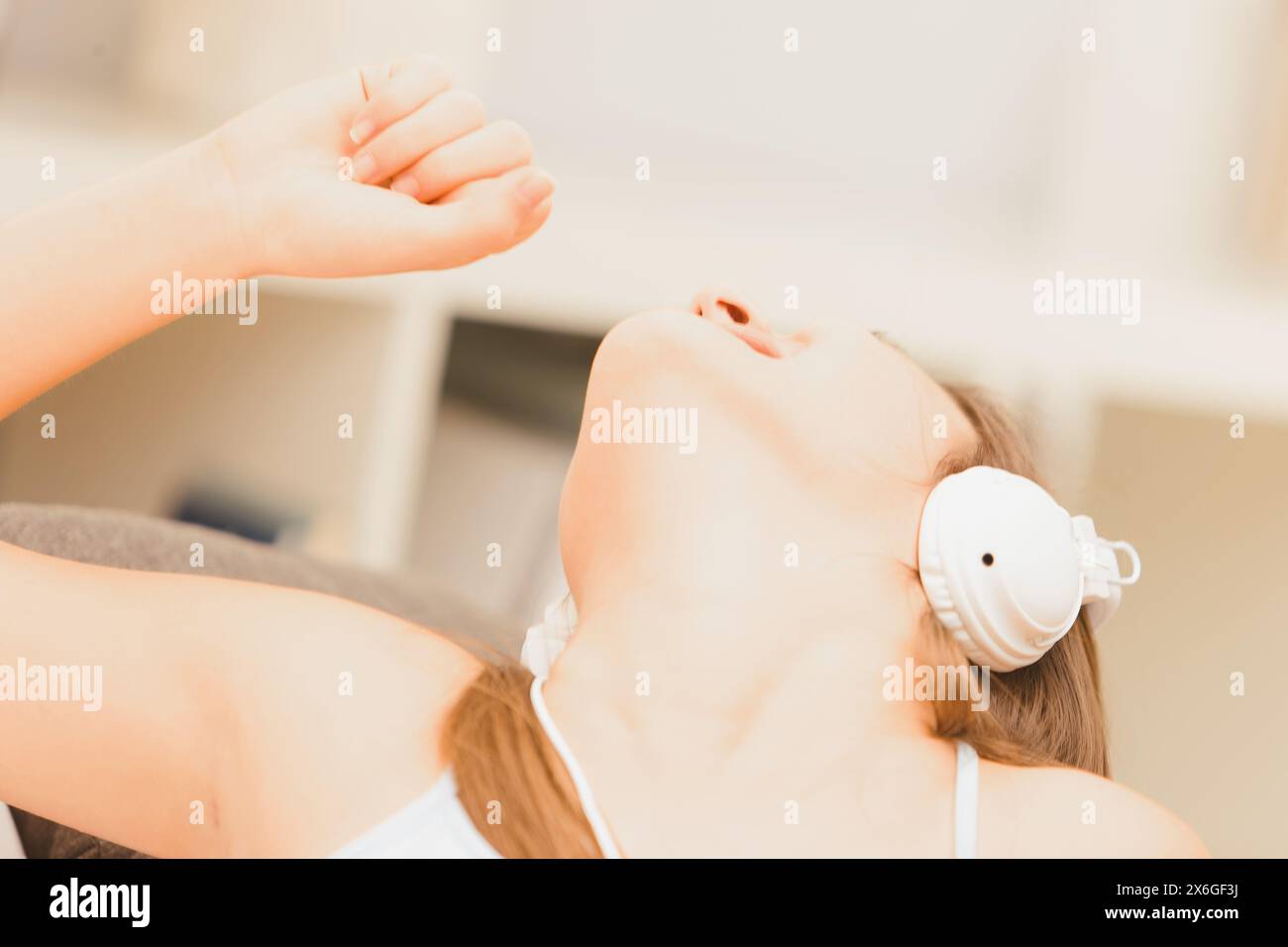 Die junge Frau singt fröhlich in ihrem Wohnzimmer, mit Kopfhörern, und spürt den Rhythmus ihrer Lieblingsmusik Stockfoto Die junge Frau singt fröhlich in ihrem Wohnzimmer, mit Kopfhörern, und spürt den Rhythmus ihrer Lieblingsmusik Stockfoto