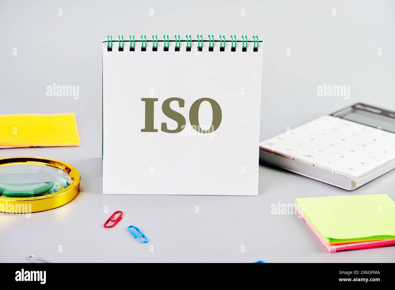 ISO. Internationale Organisation für Normung. Ein Word ISO auf einem Notizblock auf grauem Hintergrund neben Büromaterial Stockfoto