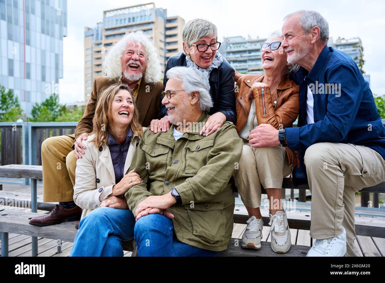 Eine Gruppe älterer kaukasischer Freunde, die Spaß haben, zusammen zu lachen und auf der Bank in der Stadt sitzen. Stockfoto